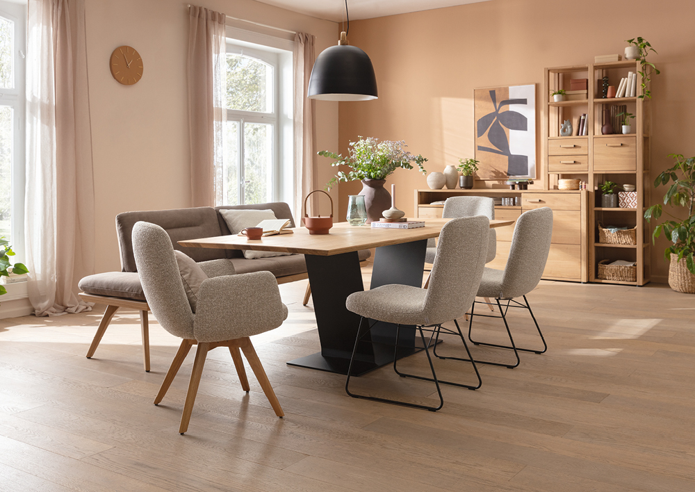Esszimmer mit Holztisch, vier Polsterstühlen, Bank und offenem Regal an beiger Wand