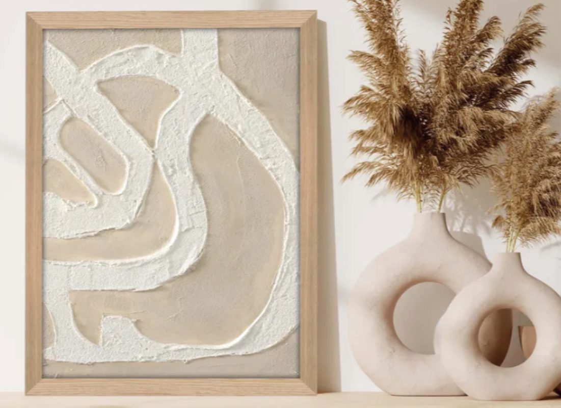 Gerahmtes Relief in Beige neben zwei Keramikvasen mit getrocknetem Pampasgras